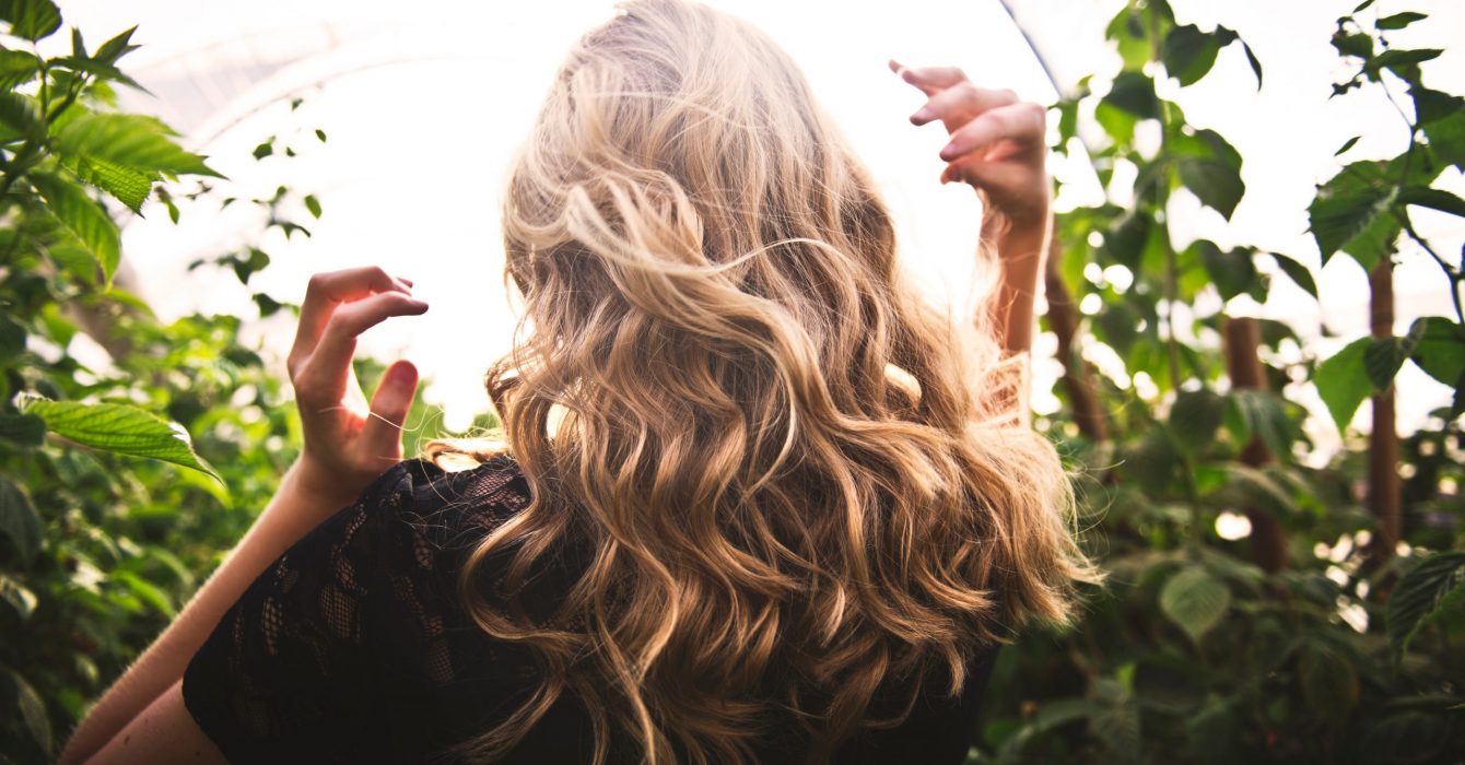 A woman walking away, her long wavy hair bouncing with her step.