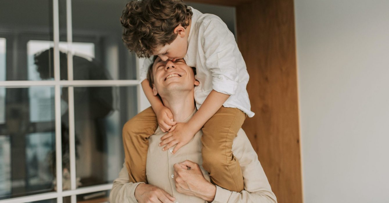 A young boy riding his father piggyback.