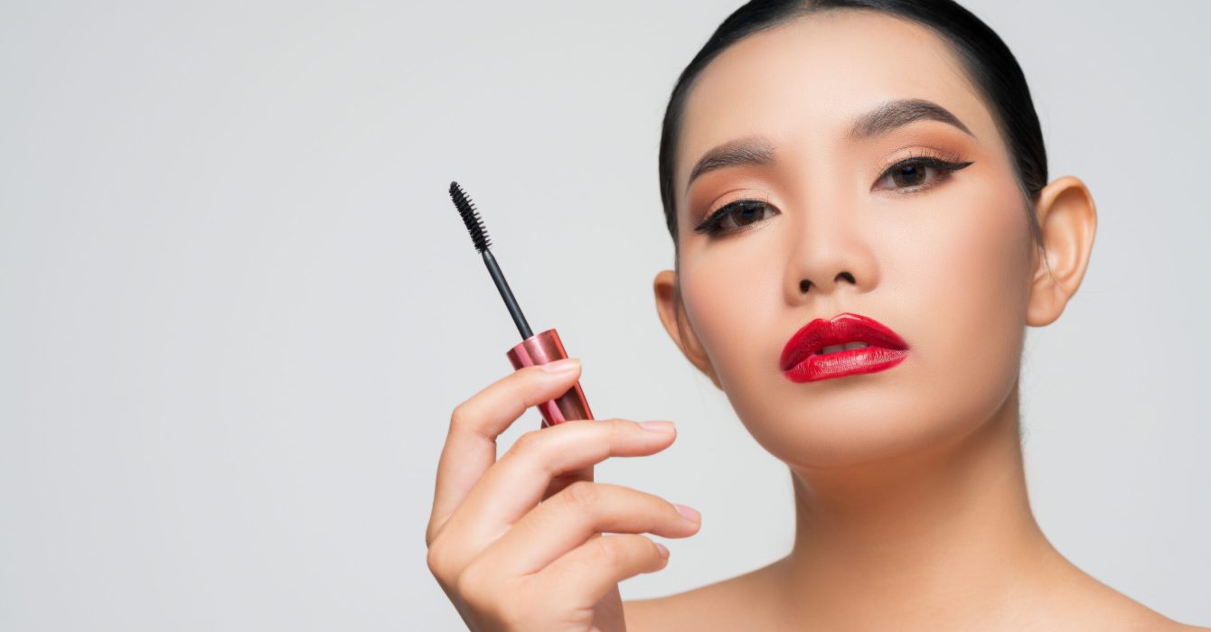 Portrait of Beautiful Asian woman with mascara in hand. Skin care healthy hair and skin close up face beauty isolated over background. Cosmetology and Spa concept.