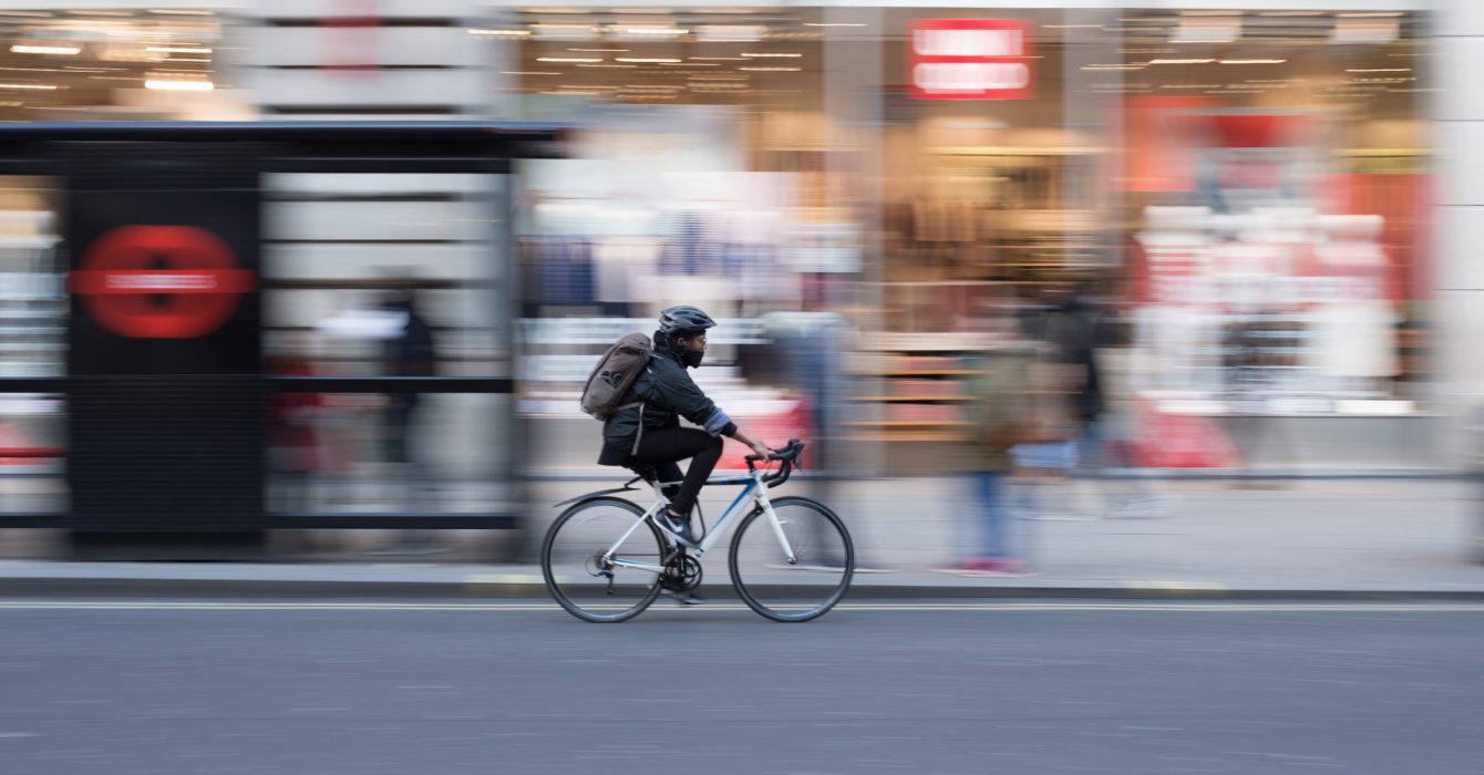 A cyclist racing by a London high street.