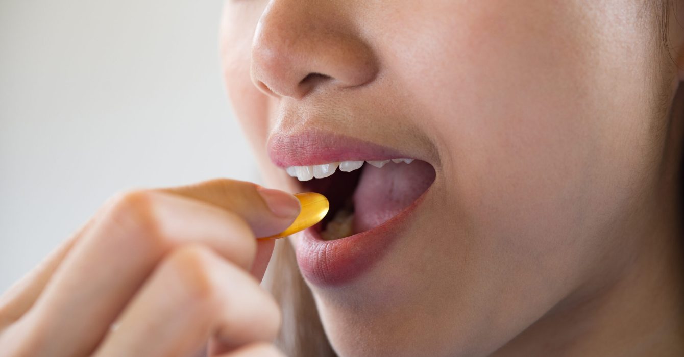 Young woman taking medicine pill after doctor order