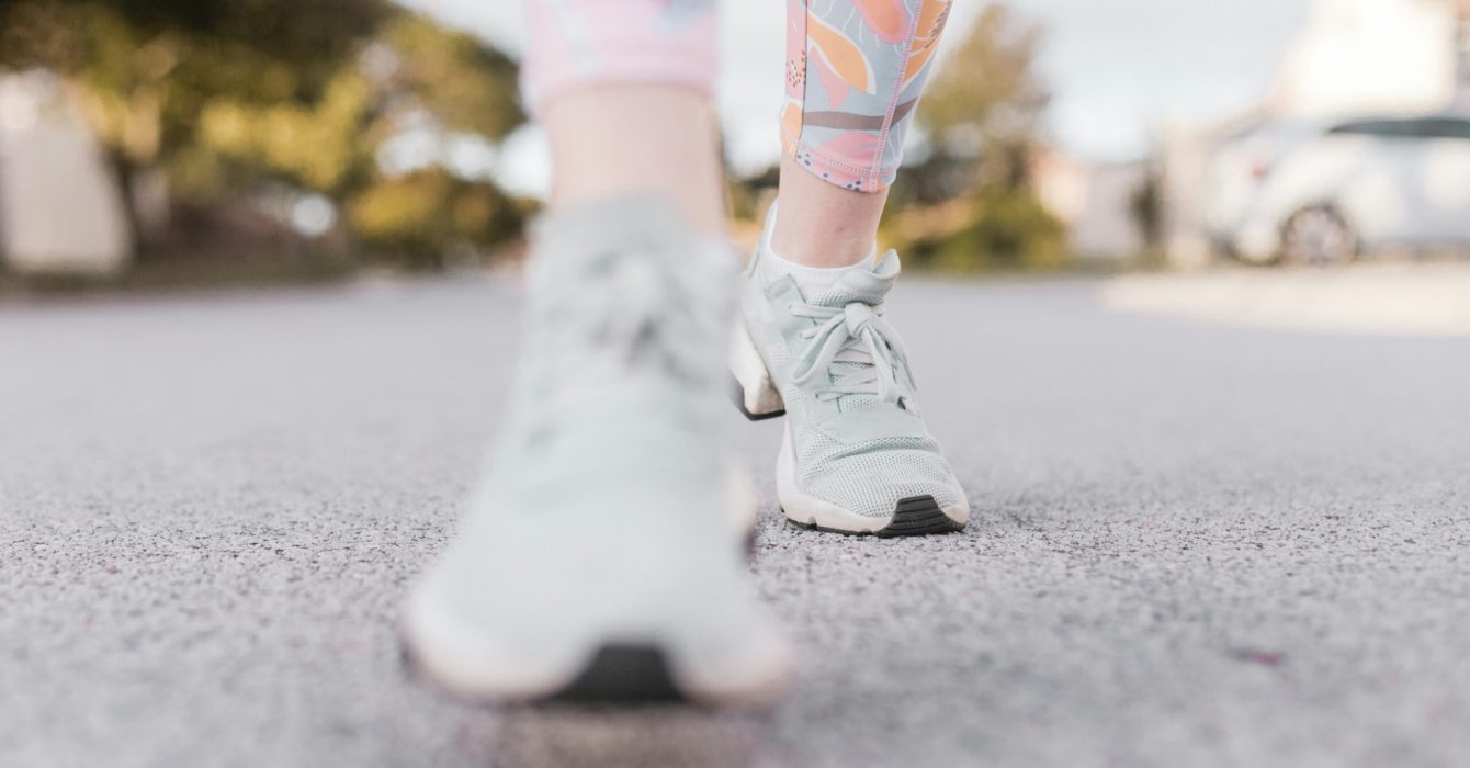 bottom of woman's legs in workout leggings and trainings walking on pavement