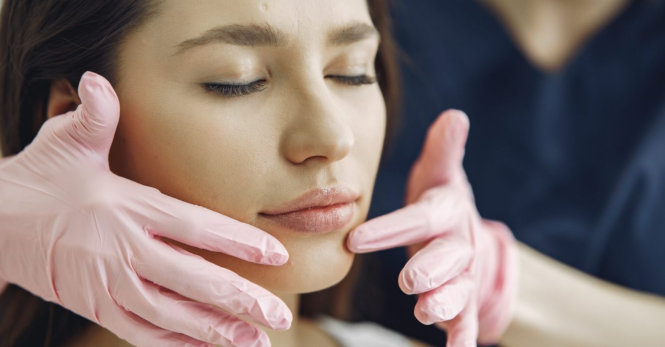 Cosmetologist holds hands near client's face. Woman with cosmetologist. Lady in a beauty studio.