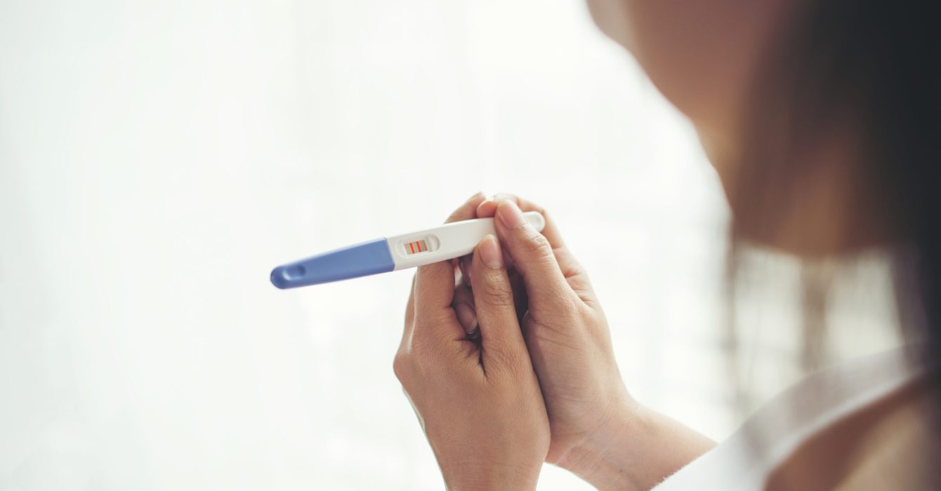 Young woman hand holding pregnancy test
